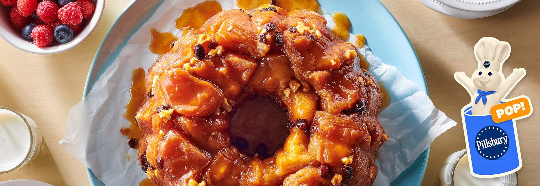 Monkey bread with caramel glaze and nuts with a bowl of berries on the side.