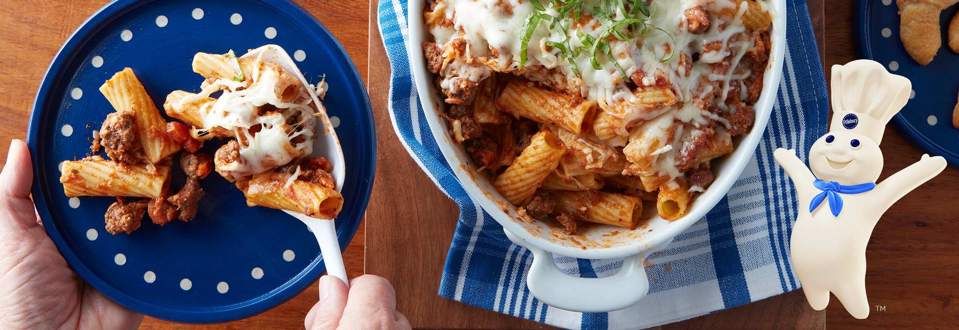 Baked rigatoni with beef and cheese next to a plate with a serving of pasta.