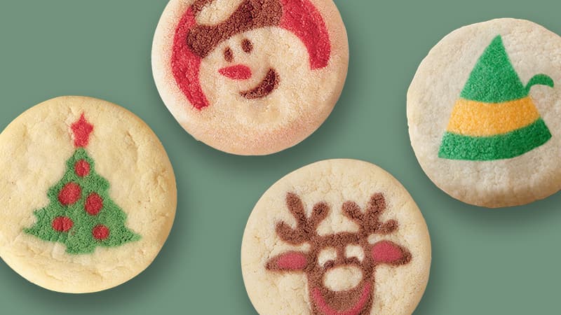 Cookies with Christmas-themed decorations: a Christmas tree, a snowman face, a reindeer, and an elf hat.